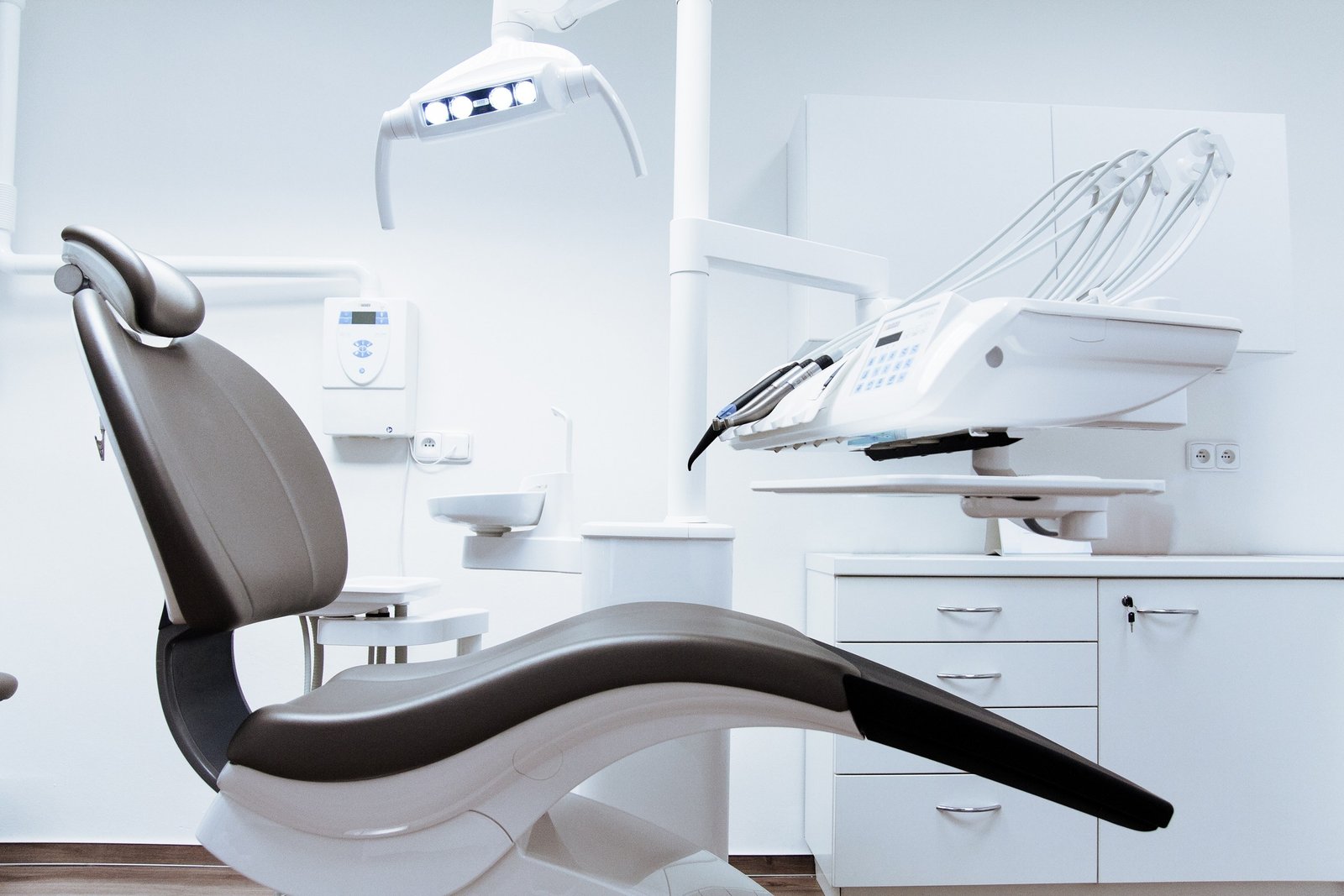 Dental chair, overhead light and instrument unit in a treatment room.