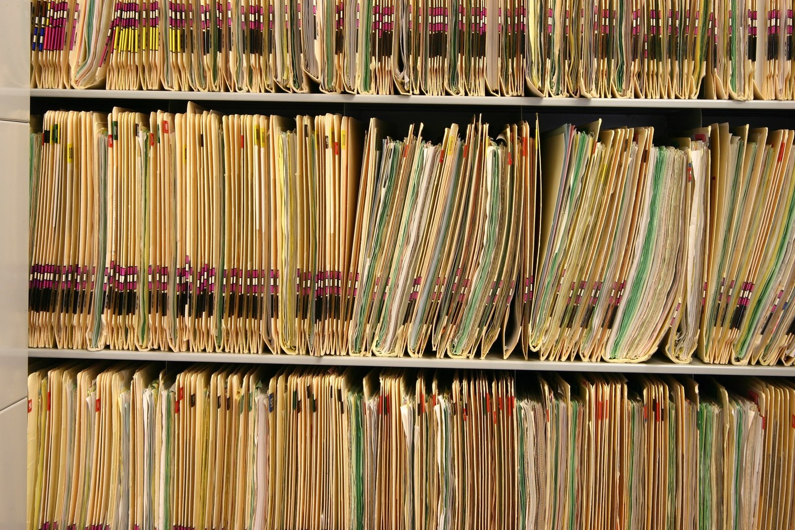 Rows of paper folders stored on shelving in a records room.