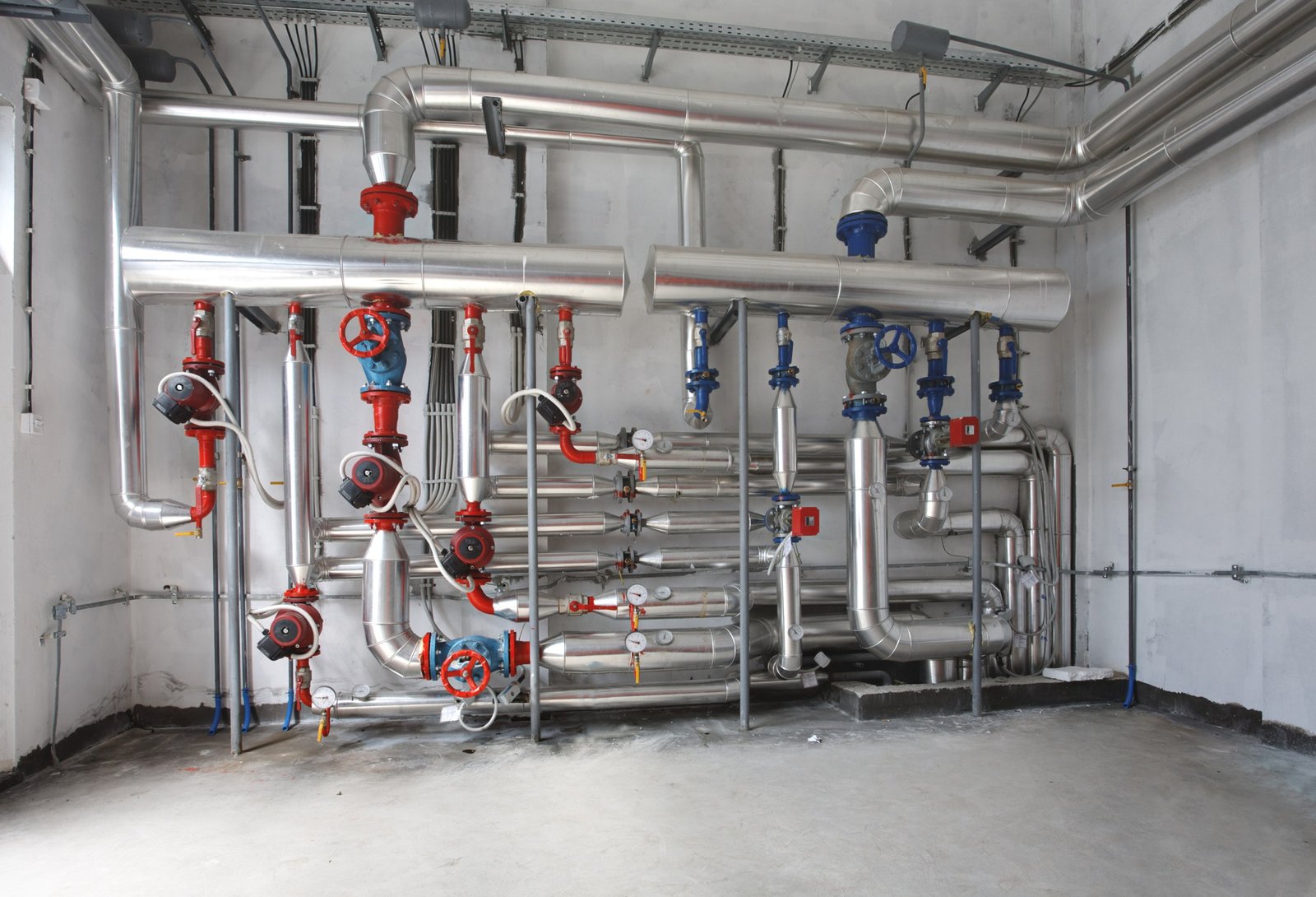 Exposed pipework and valves in a building plant room.