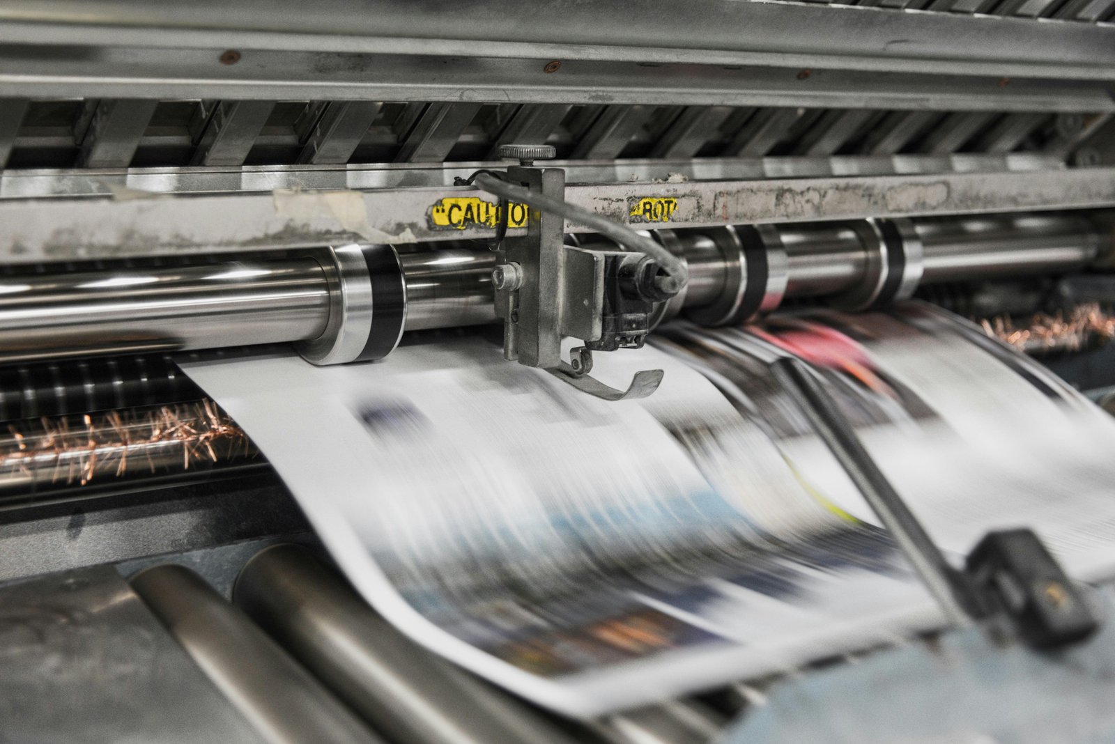 Printed sheets moving through the rollers of a printing press.